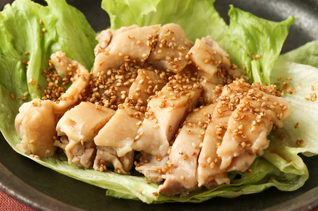 Furikake saupoudré sur du poulet coupé en tranches, disposé sur de la laitue dans une assiette noire