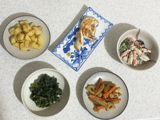 Assortiment d'accompagnements japonais dans des plats variés sur un plan de travail blanc-gris