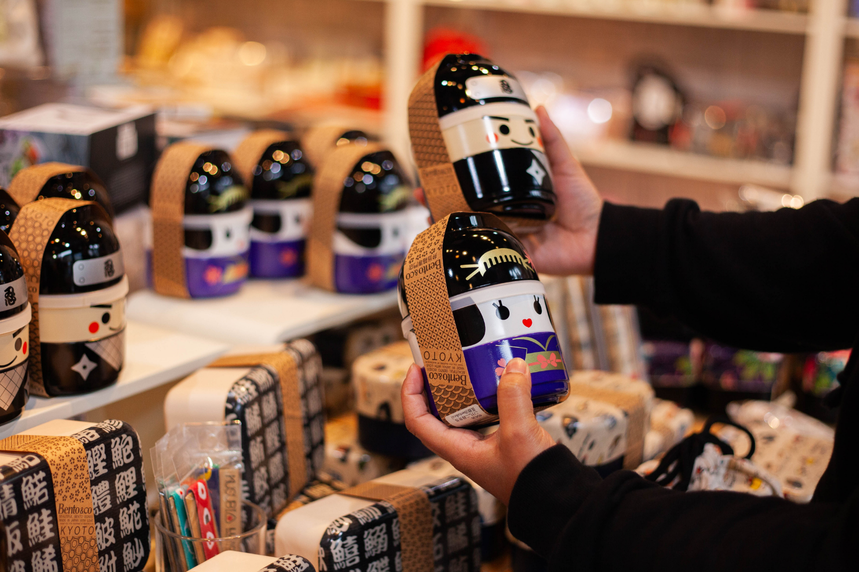 Personne regardant un bento en forme de poupée Kokeshi dans un magasin de bento