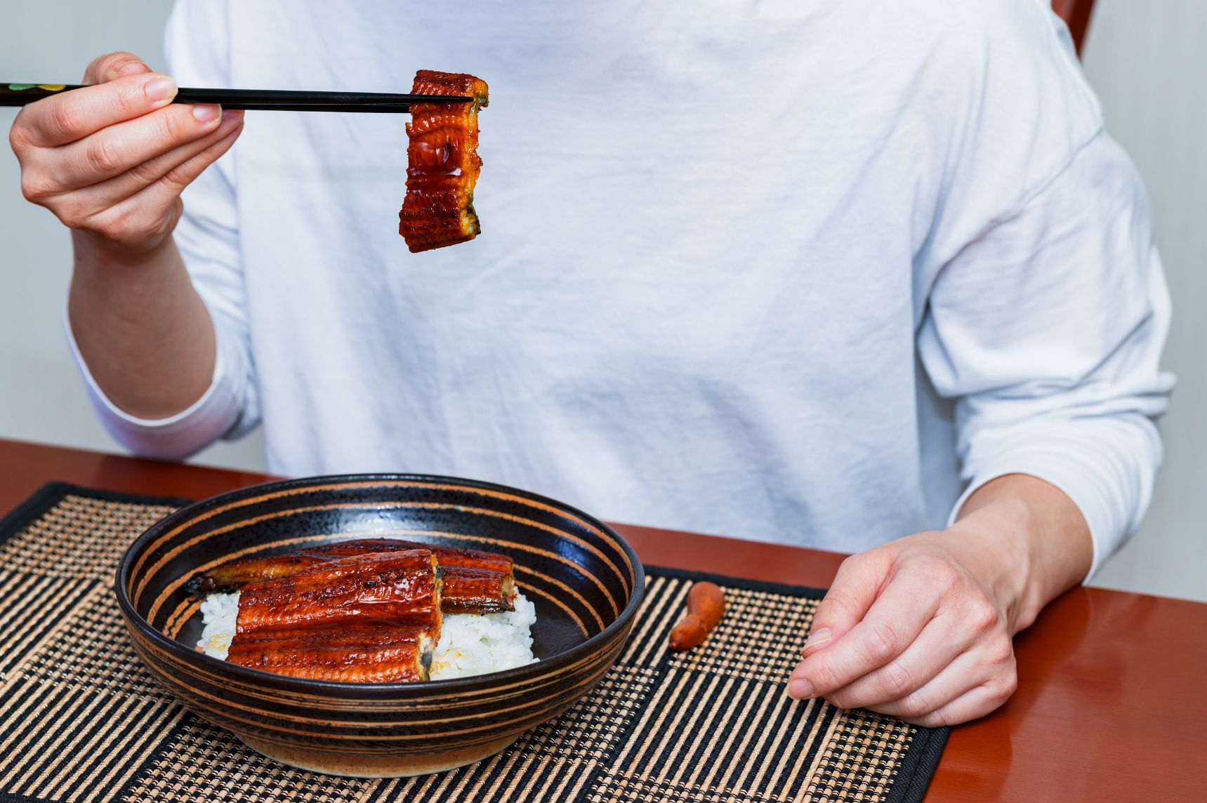 Personne mangeant de l'anguille sur du riz à la maison