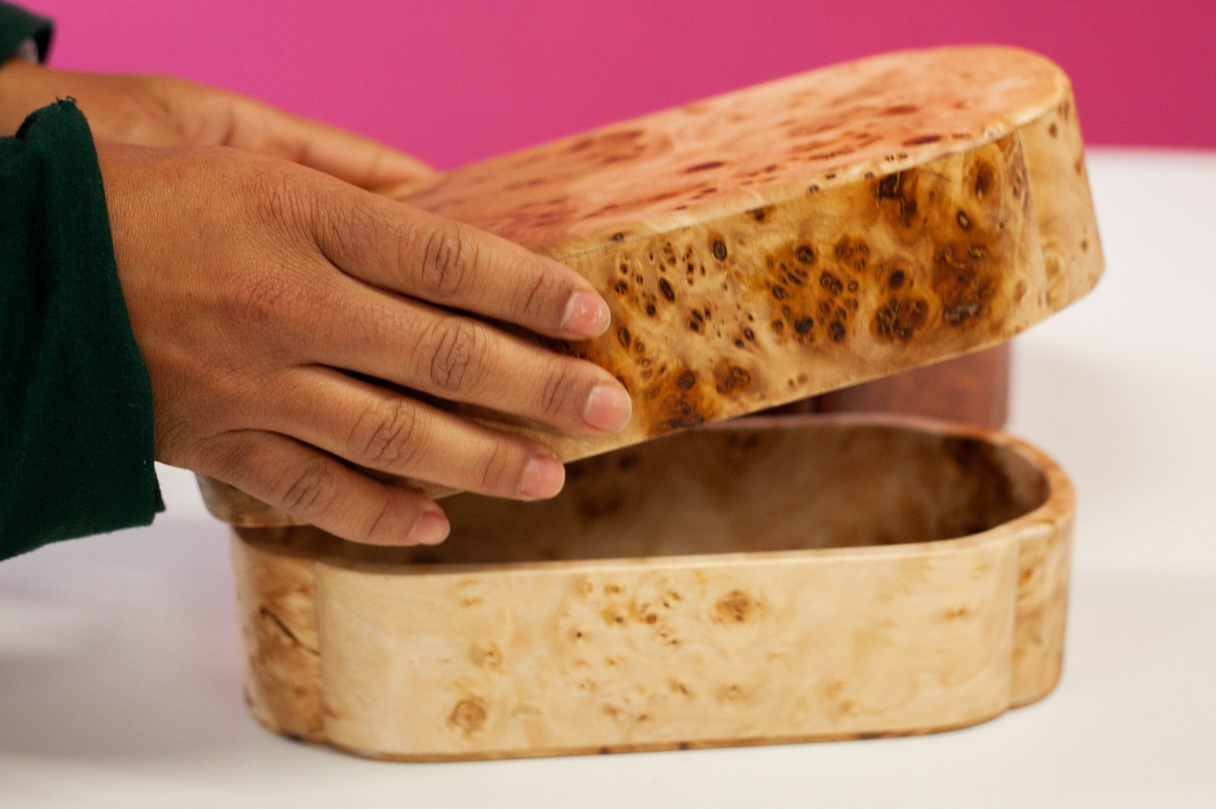 Personne ouvrant une boîte à bento artisanale en bois sur une table blanche